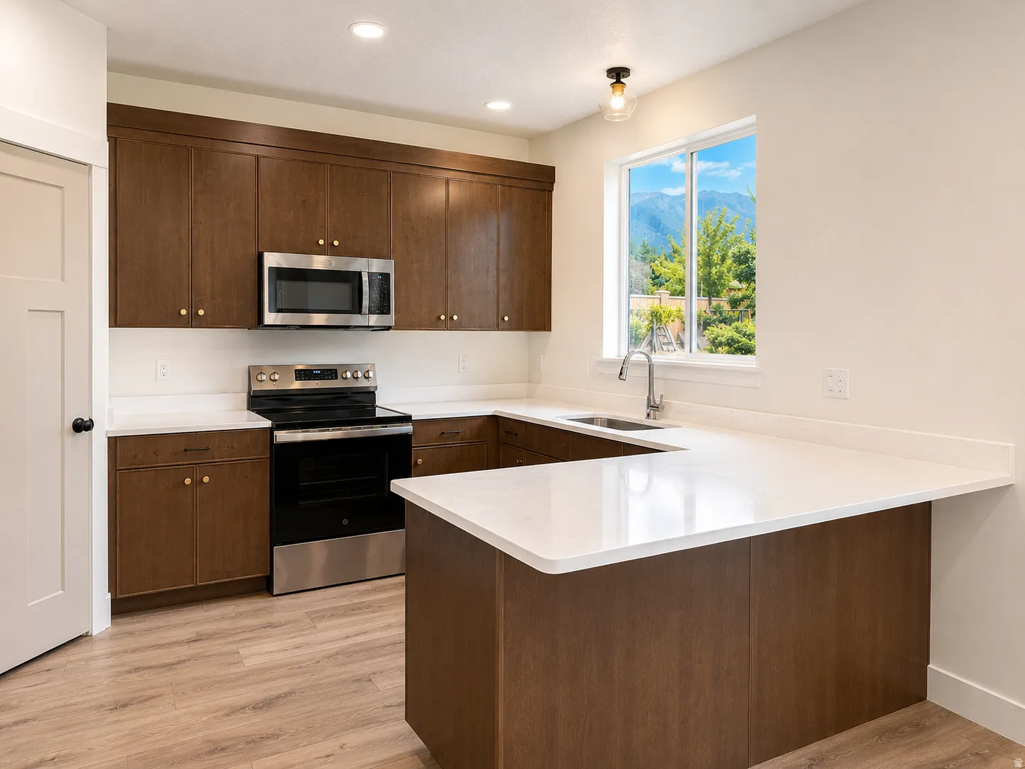 U-shaped kitchen featuring wood cabinetry, white countertops, stainless steel appliances, and wood-finish flooring