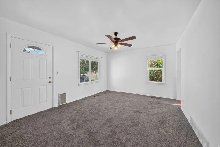 White painted walls, ceiling fan with integrated lighting, and gray carpet flooring
