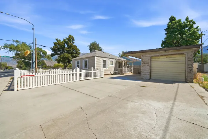 Detached garage with a roll-up door, covered carport, and concrete driveway