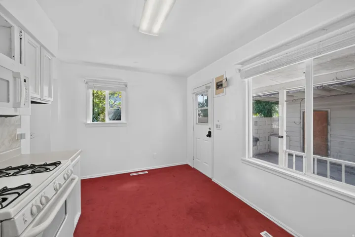 White upper cabinetry, white microwave, and a white gas range with a matching backsplash