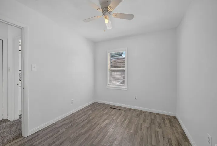 Wood-finish flooring, ceiling fan with integrated lighting, white baseboards, and a window with blinds