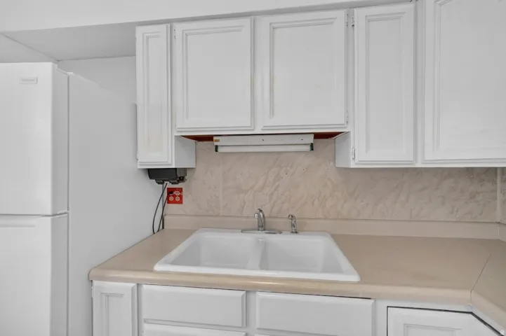 White cabinetry with panel detailing, light-toned countertop, and dual-basin sink