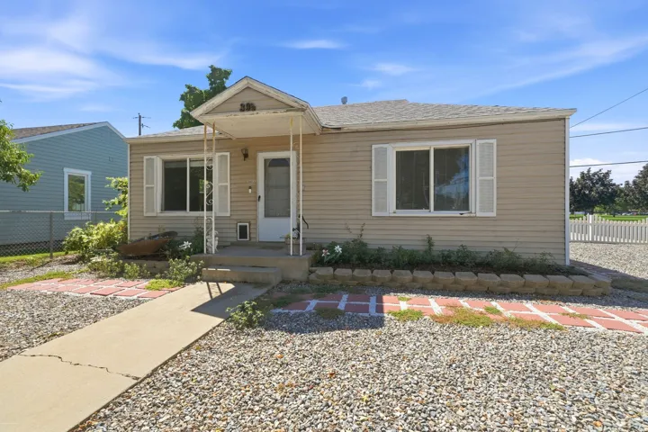 Front facade with horizontal siding, covered porch entry, and a gravel front yard