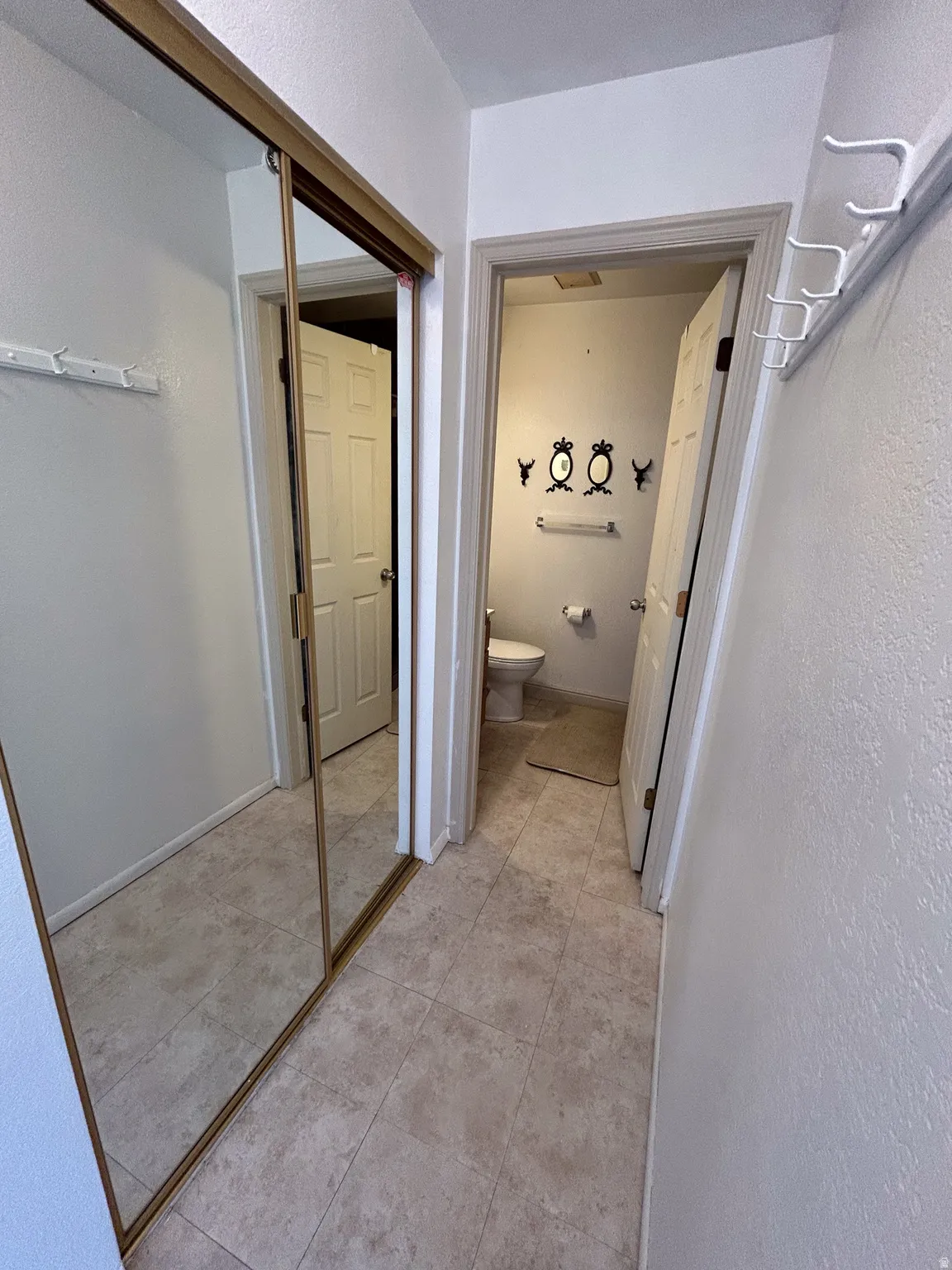 Recessed lighting, tile flooring, mirrored closet doors, and coat hooks