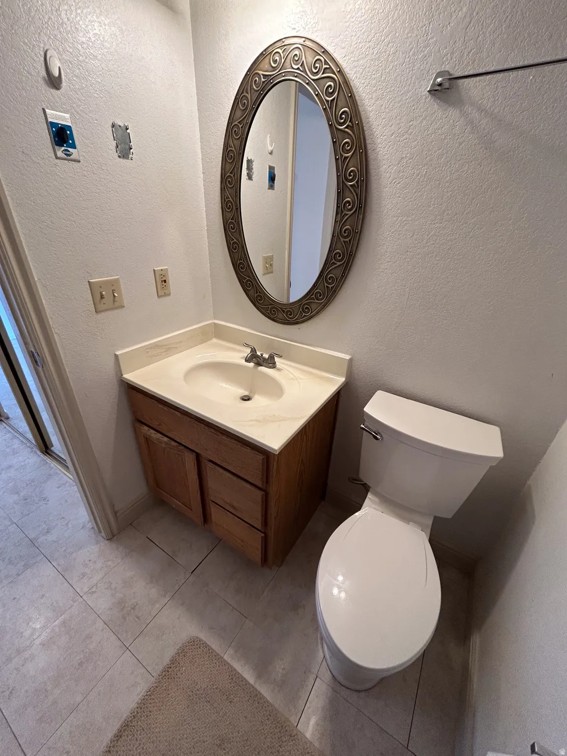 Vanity with a built-in sink and wood-finish cabinetry, complemented by a decorative framed mirror