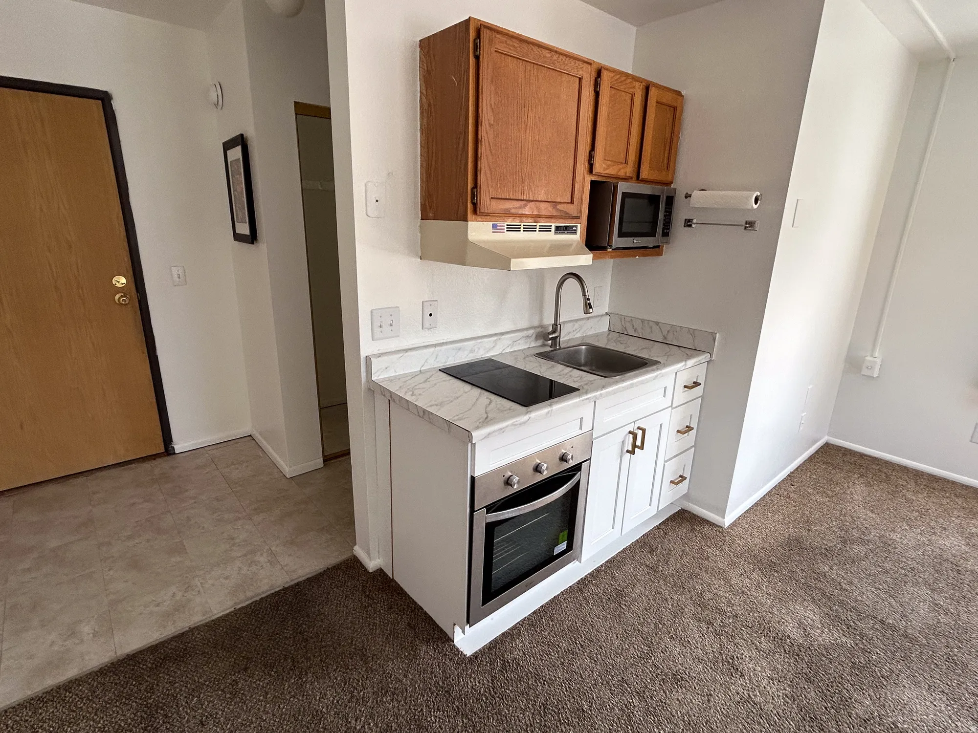 Galley kitchen featuring a stainless steel sink, built-in cooktop, and integrated oven