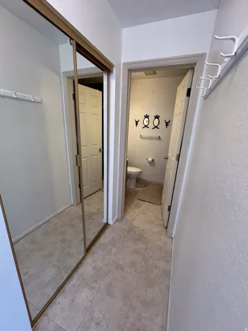 Recessed lighting, tile flooring, mirrored closet doors, and coat hooks