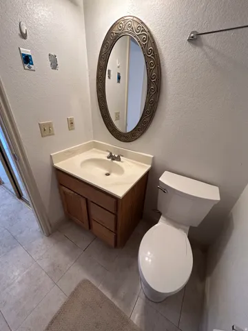 Vanity with a built-in sink and wood-finish cabinetry, complemented by a decorative framed mirror
