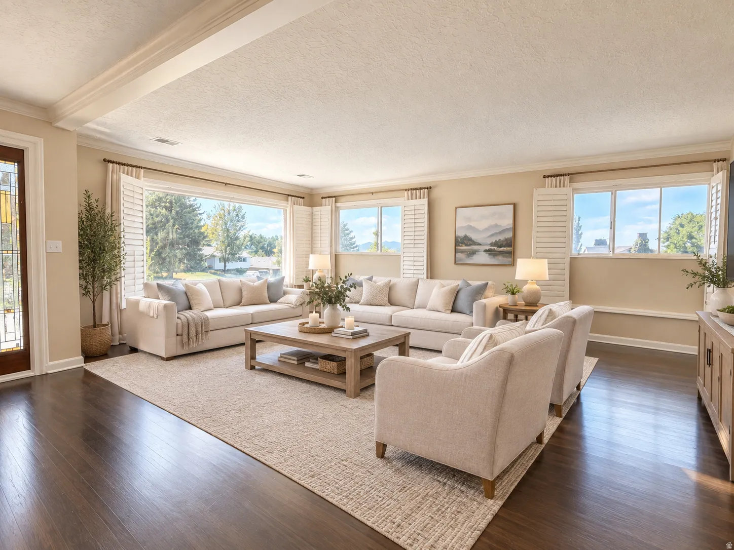 Wood-finish flooring with a neutral area rug, large picture window with white plantation shutters, additional windows with white plantation shutters, stained glass entry door, and crown molding