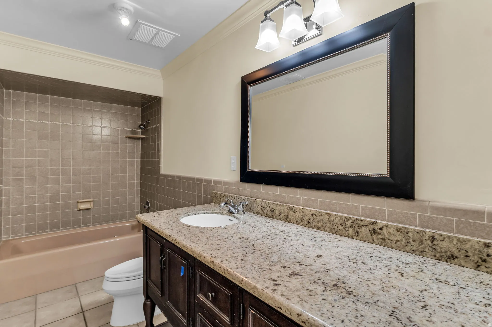 Vanity with a light-toned countertop, integrated sink, and dark wood-finish cabinetry