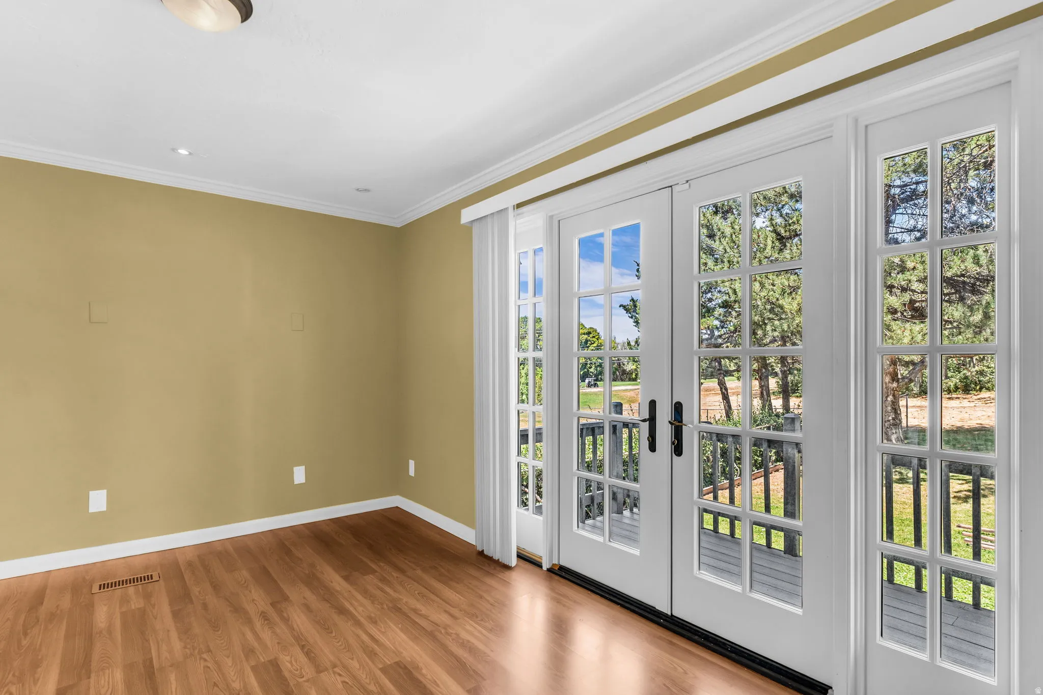 Wood-finish flooring with crown molding and recessed lighting