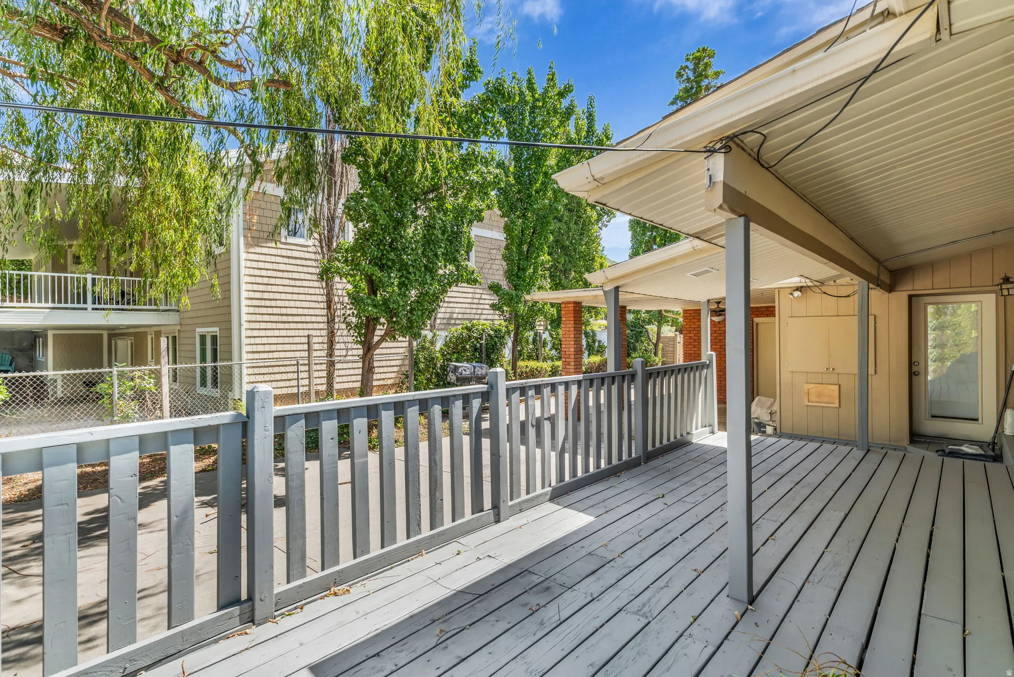 Covered wood-finish deck with a painted railing and a glass-paneled exterior door