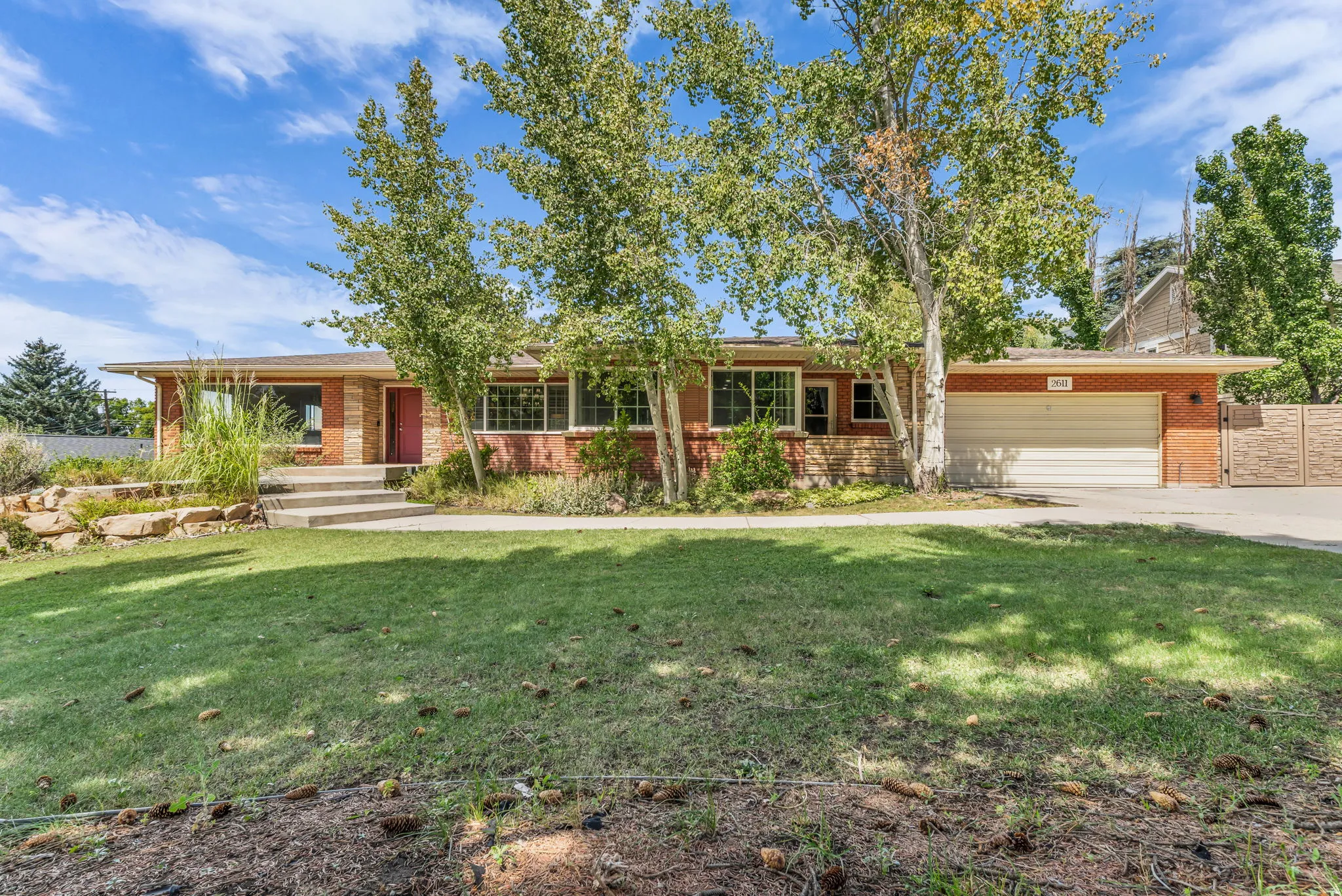 Brick exterior with a prominent garage, concrete driveway, and mature landscaping