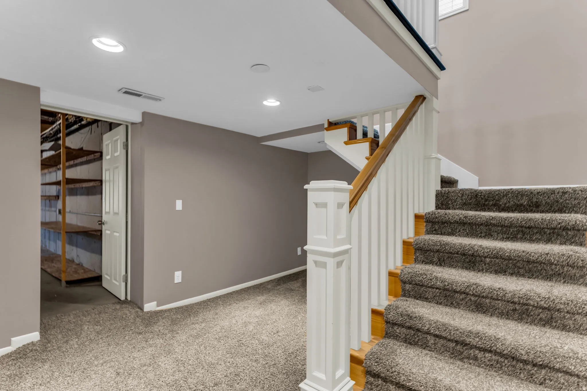 Carpeted staircase with white balusters and wood handrail