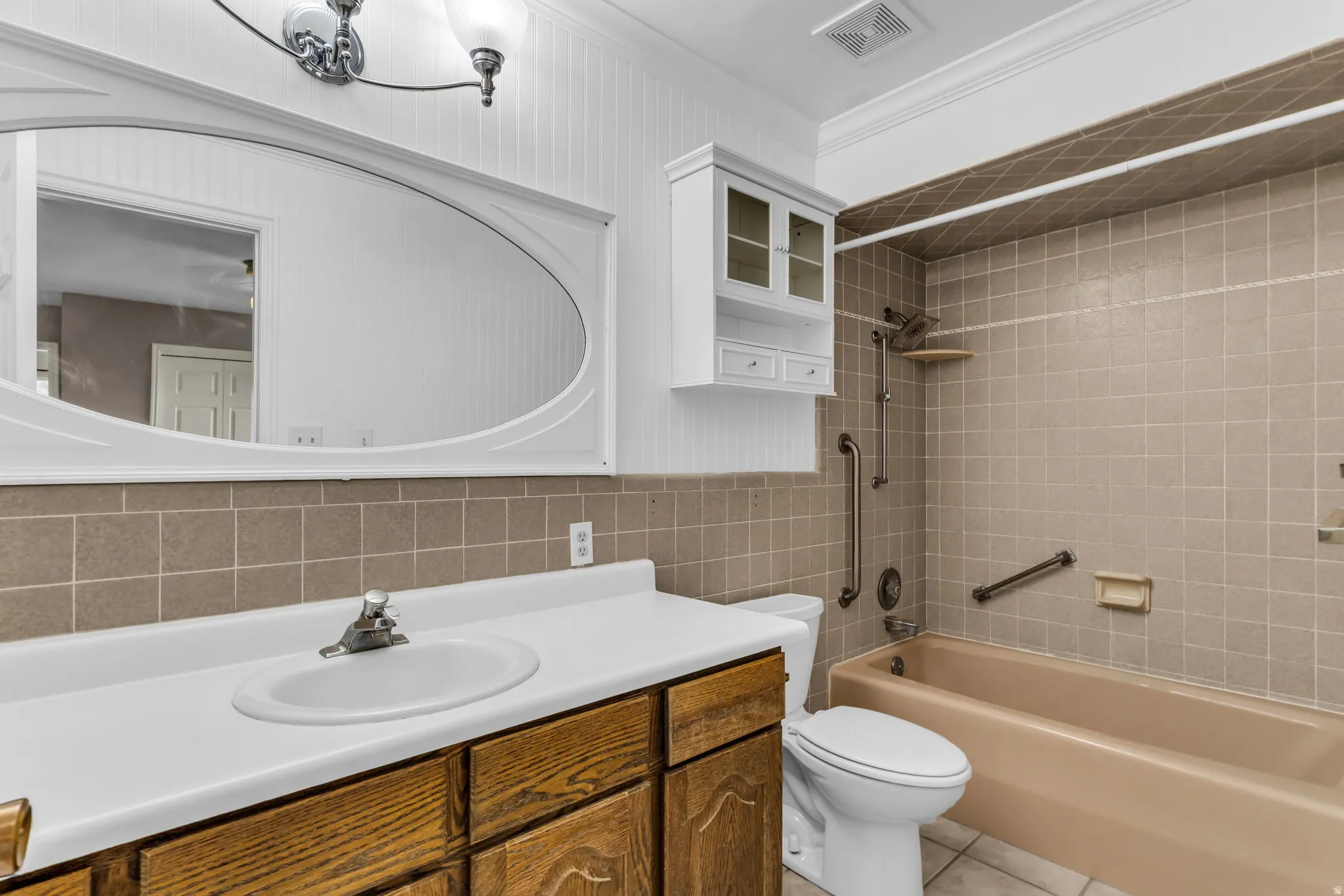 Bathroom featuring a wood-finish vanity with an integrated sink, a white countertop, and a tiled shower/bathtub combination