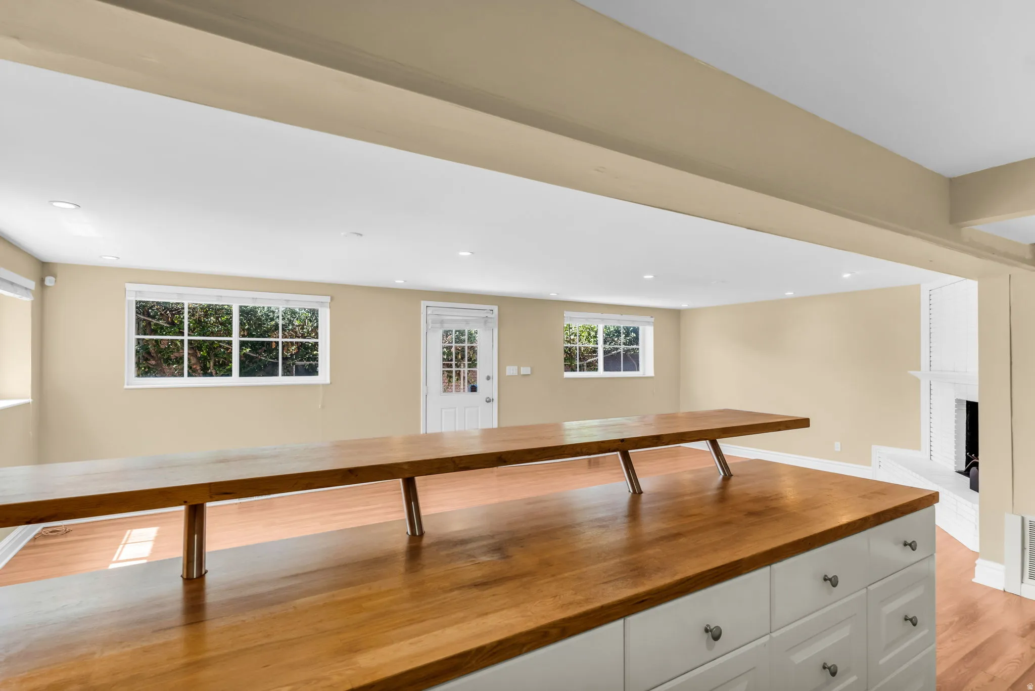 Wood-finish flooring throughout, white cabinetry with silver hardware, recessed ceiling lighting, and a white fireplace
