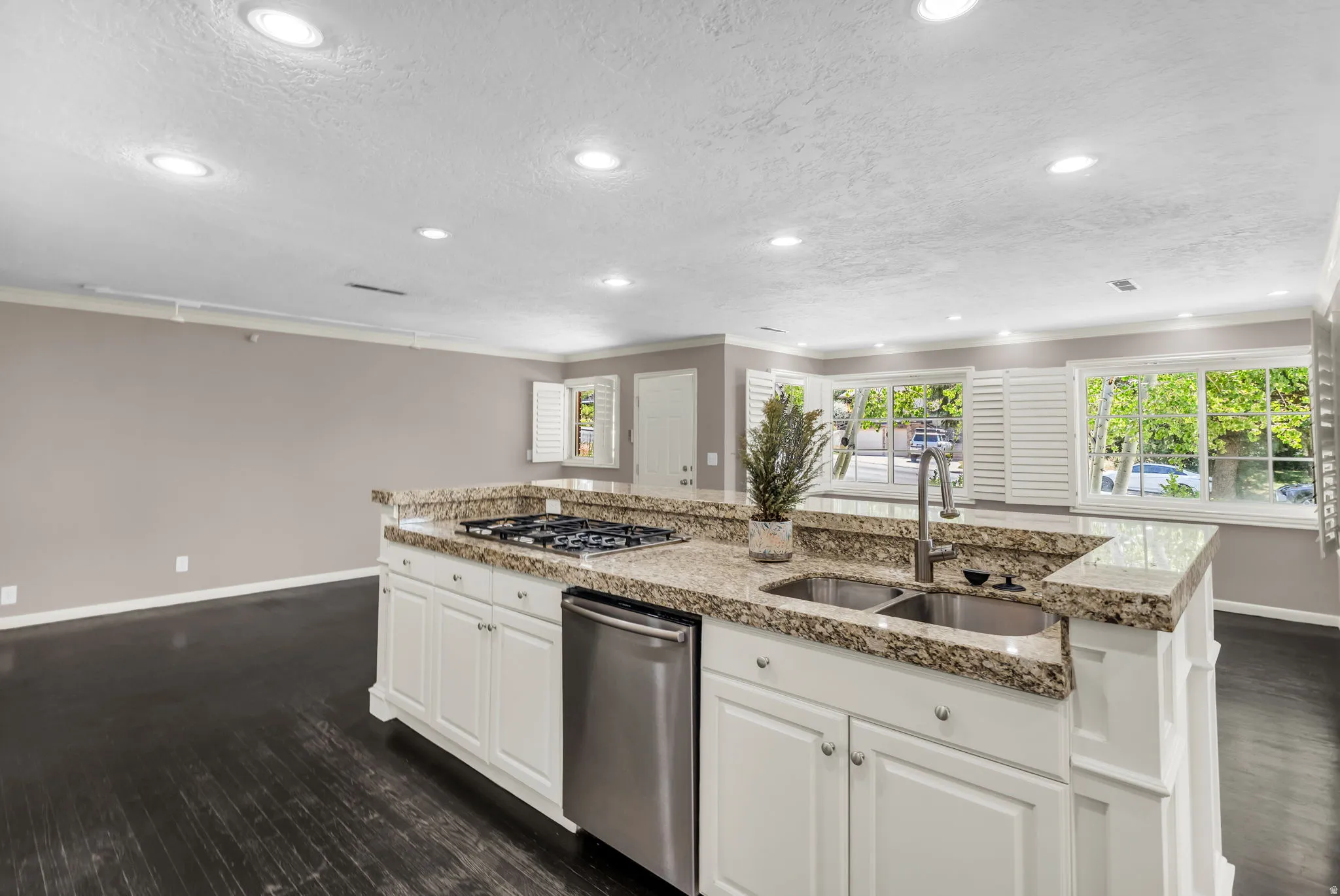 Kitchen island with granite countertops, stainless steel appliances, recessed lighting, white cabinetry, and dark wood-finish flooring