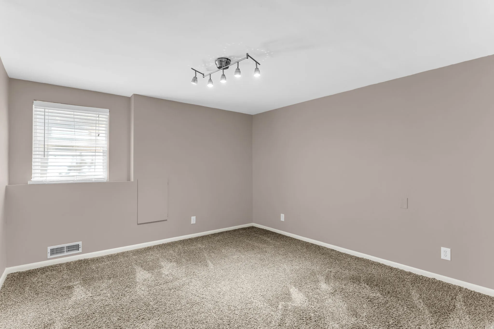Plush carpet flooring, neutral wall tones, white trim, and a window with blinds