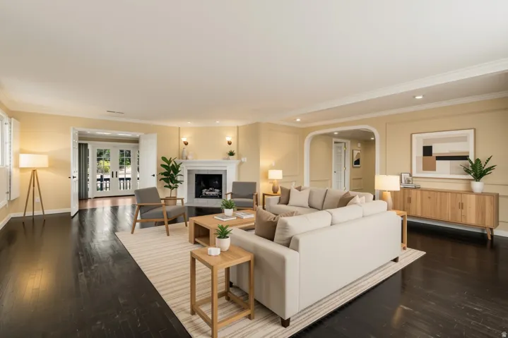 Expansive living area featuring dark wood-finish flooring, a white mantel fireplace, and a light-colored wall finish