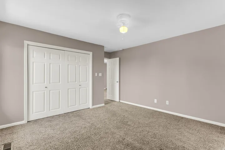 Neutral-toned walls, carpeted flooring, and white trim