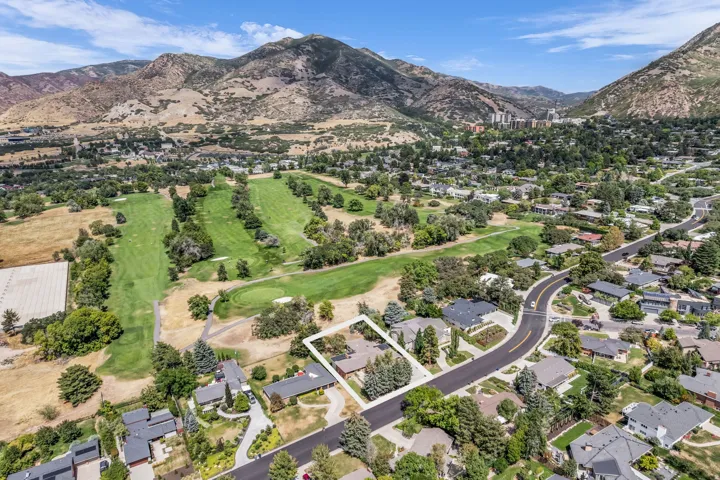 Property situated on a residential street, bordered by a golf course, with mountainous terrain in the background