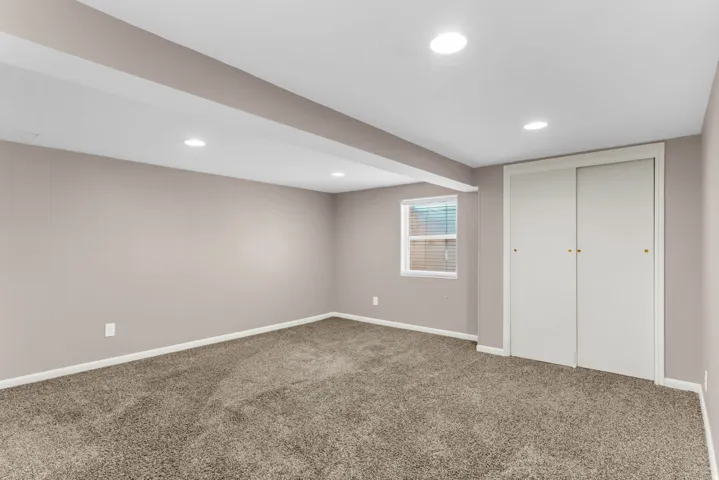 Recessed lighting, neutral wall finishes, carpet flooring, a window with blinds, and white sliding closet doors