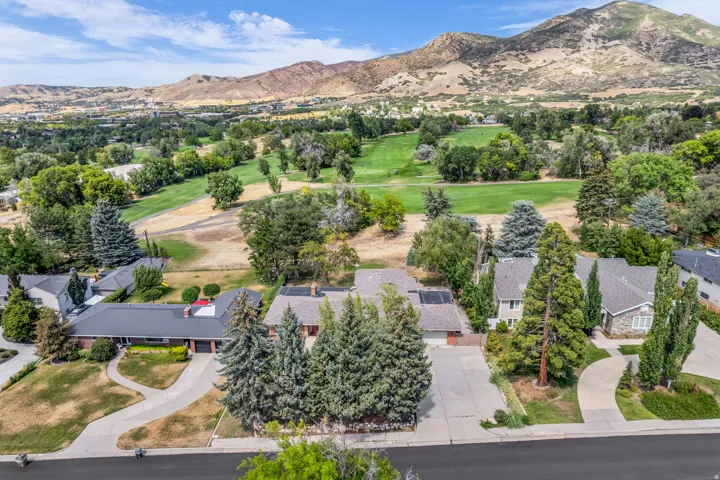 Property featuring a paved driveway, mature trees, and a mountain backdrop
