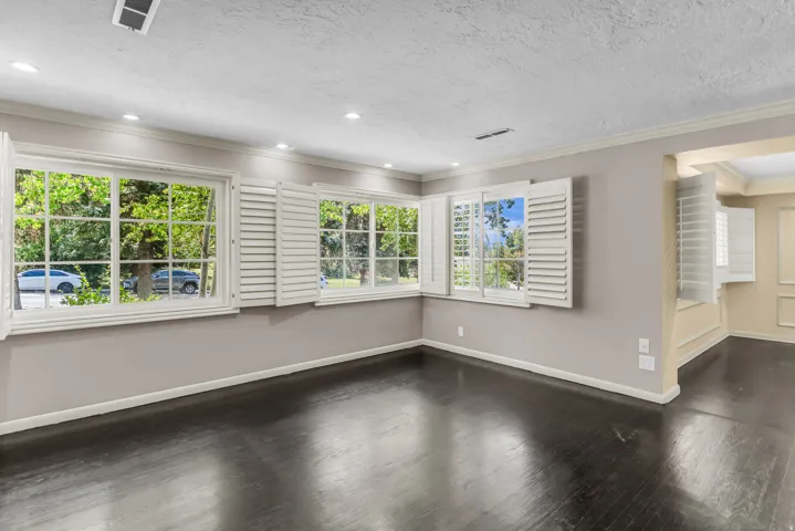 Dark wood-finish flooring, recessed lighting, white louvered window shutters, and white crown molding