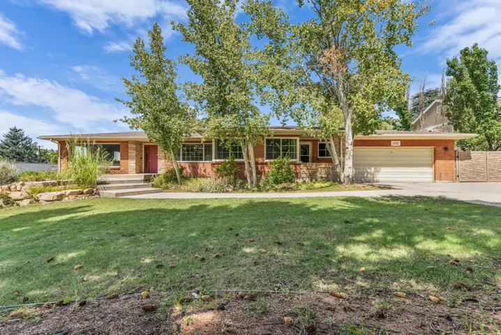 Brick exterior with a prominent garage, concrete driveway, and mature landscaping
