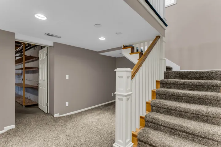 Carpeted staircase with white balusters and wood handrail