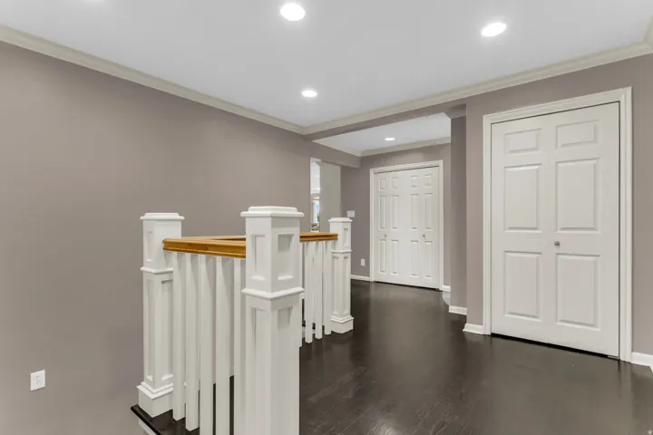 Hardwood-finish flooring, recessed lighting, crown molding, white trim, and bi-fold doors