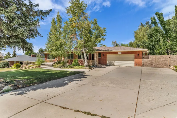Red brick exterior with stone accents, attached garage, concrete driveway, and mature landscaping