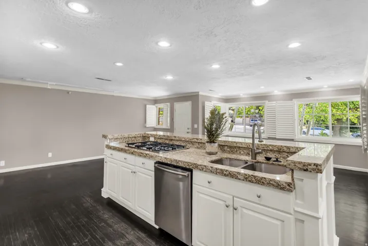Kitchen island with granite countertops, stainless steel appliances, recessed lighting, white cabinetry, and dark wood-finish flooring