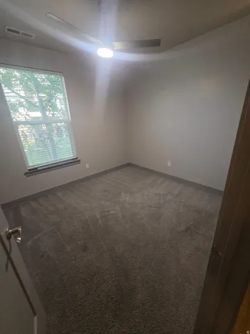 Ceiling fan with integrated lighting, window with blinds, carpeted flooring, and painted walls