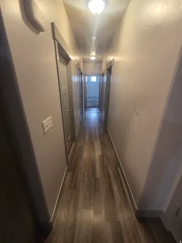 Wood-finish flooring throughout the hallway, complemented by recessed lighting and a neutral wall color