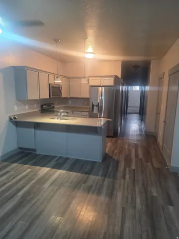 Kitchen featuring light gray cabinetry, stainless steel appliances, a counter-height island, and pendant lighting