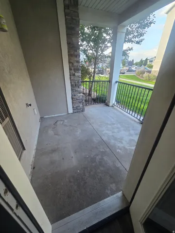 Concrete patio with stone-clad column, white railing, and stucco exterior