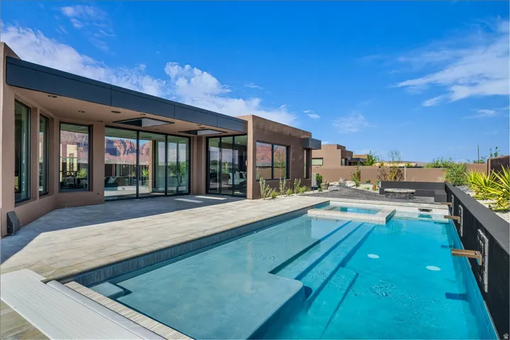 Modern exterior with a flat roofline, floor-to-ceiling glass doors, and a rectangular pool with integrated spa