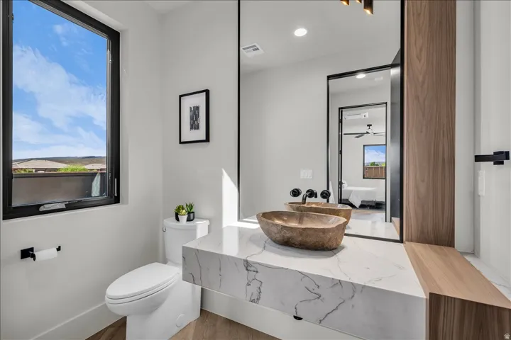Floating vanity with a stone vessel sink, wall-mounted faucets, and a full-height mirror