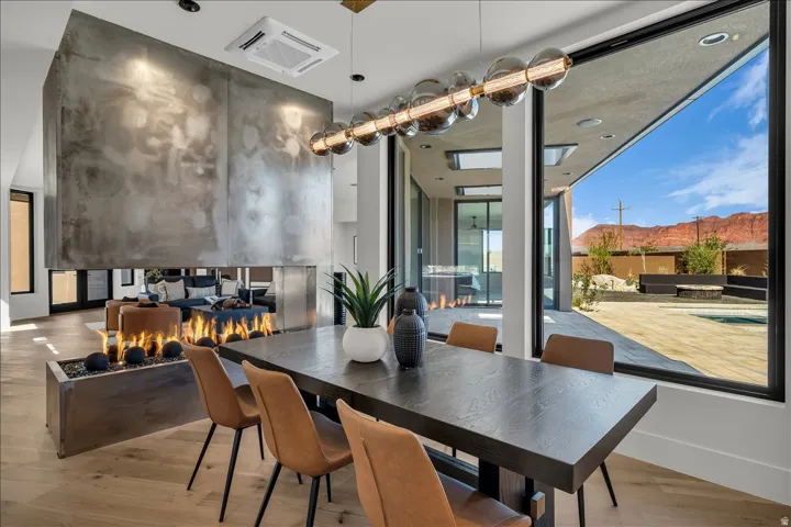 Open-concept dining area with wood-finish flooring, a linear chandelier, and a built-in fireplace feature