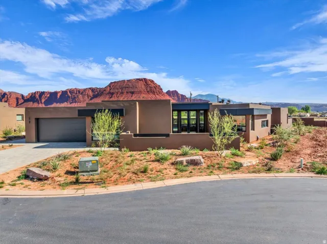 Contemporary desert architecture featuring a stucco exterior, integrated garage, and expansive window placements