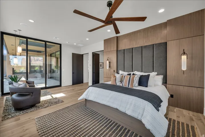 Wood-finish flooring, recessed lighting, and a dark-paneled headboard wall with integrated sconces
