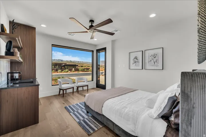 Hardwood-finish flooring, built-in cabinetry with open shelving, integrated sink with matte black faucet, expansive window, and a ceiling fan