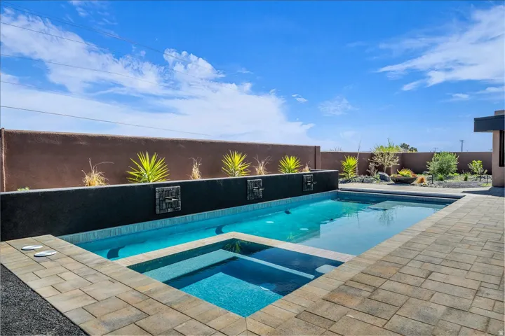 Swimming pool with integrated spa, paver patio, decorative wall fountains, and desert landscaping