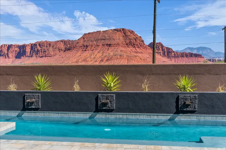 Swimming pool with integrated water features, bordered by desert landscaping and a distant mountain backdrop