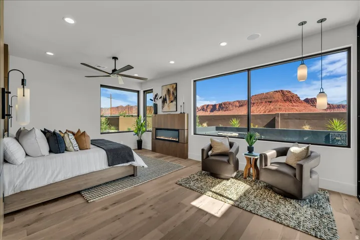 Expansive picture windows, wood-finish flooring, a built-in fireplace, recessed lighting, and a ceiling fan