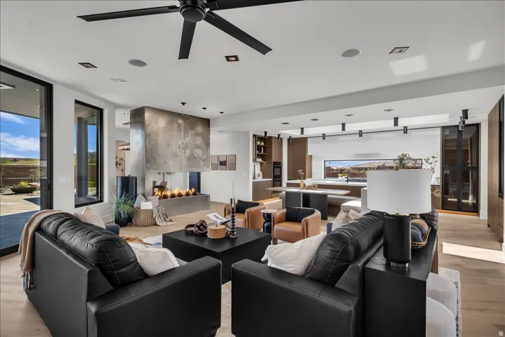 Open-concept living area featuring a linear fireplace, wood-finish flooring, and a contemporary ceiling fan