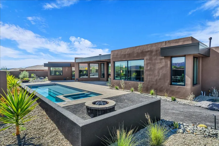 Outdoor living area featuring a rectangular pool with integrated spa, a round fire pit, and a spacious paved patio