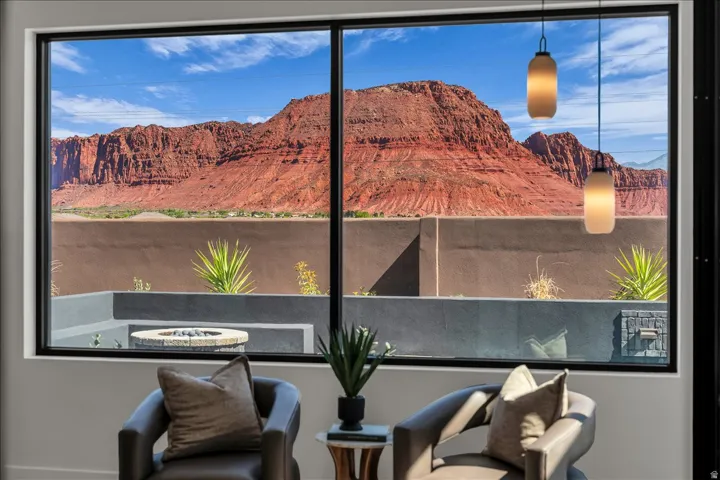 Expansive picture windows offering mountain scenery, with two pendant light fixtures, and a patio featuring a fire pit