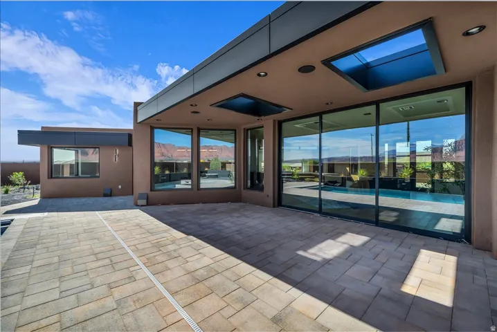 Extensive paver patio with a built-in drainage system, large sliding glass doors, multiple skylights, and recessed lighting